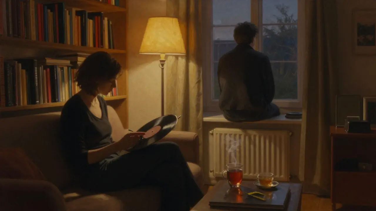 A woman playing vinyl in a cozy hotel room while a man gazes out the window, tea steaming beside him, warm lamplight filling the space.